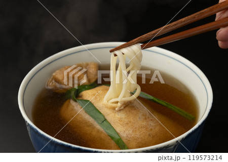 きつねうどん 巾着きつねうどん 油揚げに詰めたうどんを箸で持ち上げる きつねうどん 巾着きつねうどん 油揚げに詰めたうどんを箸で持ち上げる 119573214