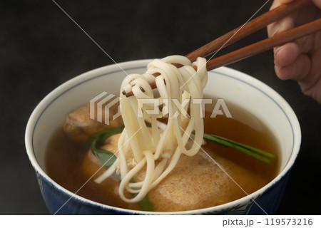 きつねうどん 巾着きつねうどん 油揚げに詰めたうどんを箸で持ち上げる きつねうどん 巾着きつねうどん 油揚げに詰めたうどんを箸で持ち上げる 119573216