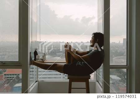 Introvert lonely man sitting at the windows enjoy being alone in apartment. Introvert lonely man sitting at the windows enjoy being alone in apartment. 119574031