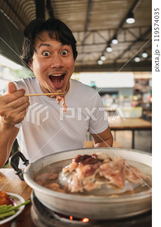 Happy and excited face man eating Moo Kra Ta or Thai BBQ buffet. 119574035