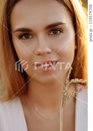 A woman is holding a stalk of wheat in her hand A woman is holding a stalk of wheat in her hand 119574708