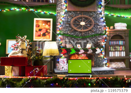 Empty cabin decorated with garlands and baubles next to isolated mockup, awaits Santa Claus at the North Pole. The festive cozy workshop having wrapped gifts ready for a magical Christmas night. 119575379