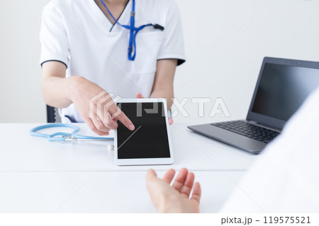 タブレットを操作して説明している医療従事者の女性 119575521