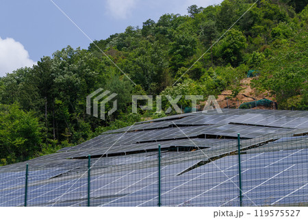 山間部の傾斜地に設置された太陽光パネルとフェンス 119575527