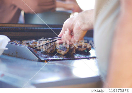 Grilling Delicacies A Skilled Chef Cooking Delicious Burgers on a Charcoal BBQ Grill Grilling Delicacies A Skilled Chef Cooking Delicious Burgers on a Charcoal BBQ Grill 119575878