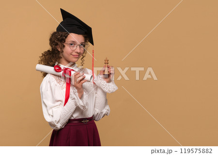 Graduate holding diploma scroll and chess king piece. 119575882