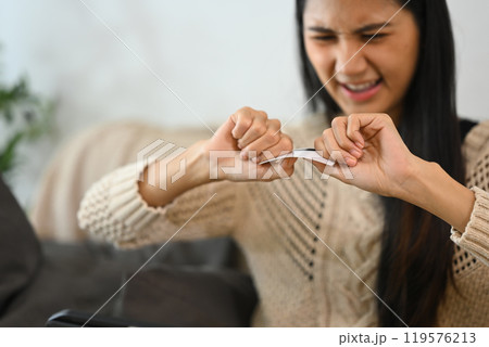 Frustrated woman destroying her credit card. Financial management and debt reduction concept 119576213