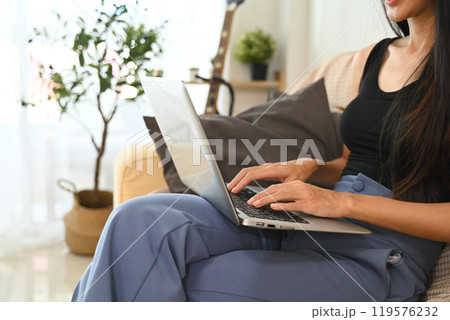 Cropped shot young woman working from home, typing on laptop keyboard Cropped shot young woman working from home, typing on laptop keyboard 119576232