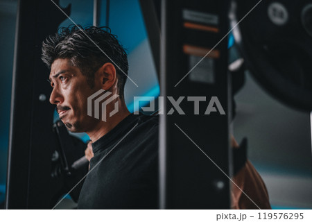 スポーツジムで下半身を鍛える40代男性 119576295