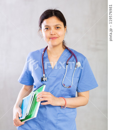 Smiling female medical student holding workbooks with lecture notes 119576981