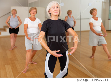 Senior women in sportswear dancing ballet inside gym Senior women in sportswear dancing ballet inside gym 119577211