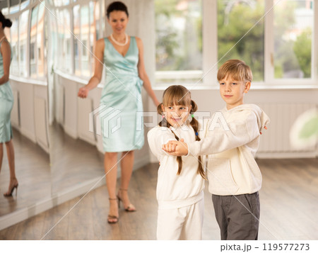 Tween boy and girl performing waltz in pair in dance hall Tween boy and girl performing waltz in pair in dance hall 119577273