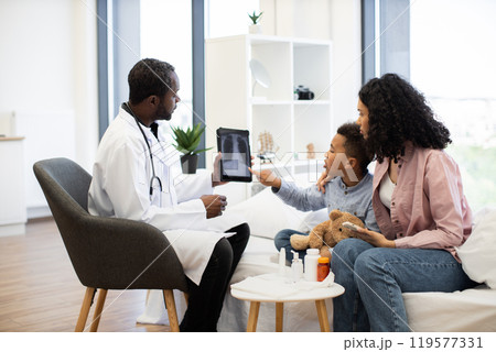Doctor explaining x-ray to concerned mother and child in clinic Doctor explaining x-ray to concerned mother and child in clinic 119577331