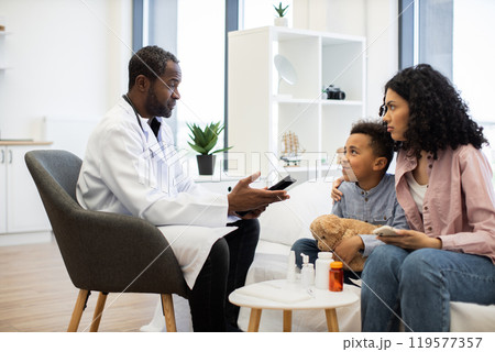 Doctor consulting boy and mother in medical office 119577357