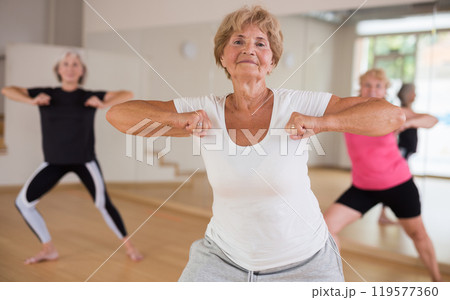 Cheerful senior woman enjoying active dancing in dance studio 119577360