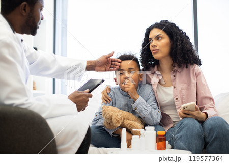 Concerned mother with sick child visiting male doctor in clinic 119577364