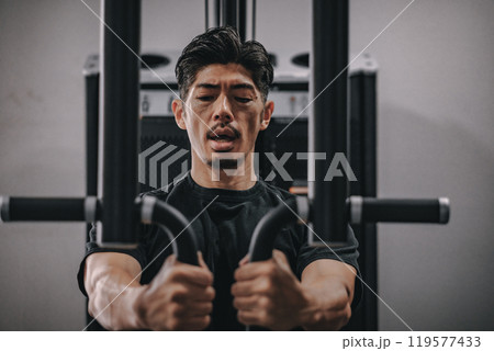 スポーツジムで上半身を鍛える40代男性 119577433