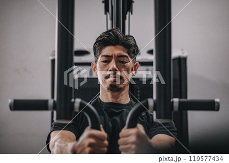 スポーツジムで上半身を鍛える40代男性 119577434