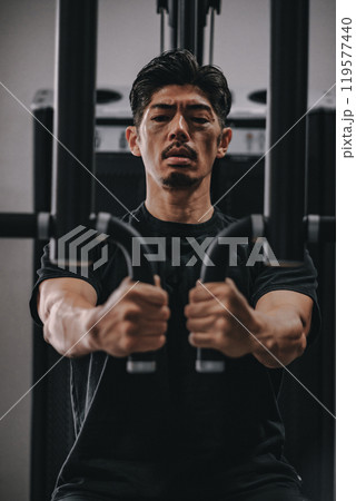 スポーツジムで上半身を鍛える40代男性 119577440