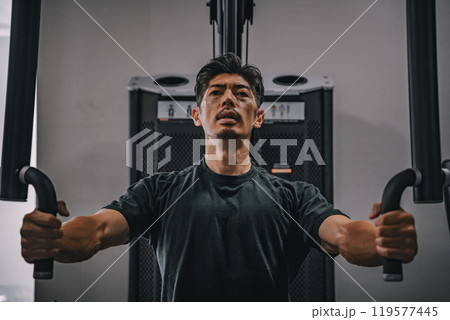 スポーツジムで上半身を鍛える40代男性 119577445