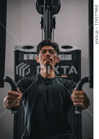 スポーツジムで上半身を鍛える40代男性 119577660