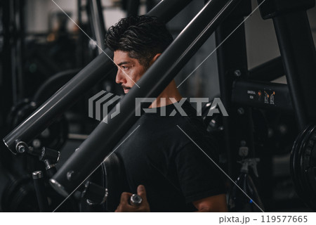 ジムで上半身をマシンを使って鍛える男性 119577665