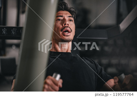 スポーツジムで上半身をマシンを使って鍛える男性の寄り スポーツジムで上半身をマシンを使って鍛える男性の寄り 119577764