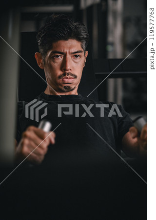 スポーツジムで上半身をマシンを使って鍛える男性の寄り 119577768