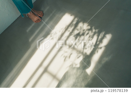裸足の女性と窓明かり 119578139