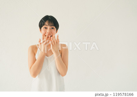 白い背景の前でキャミソール姿の若い女性の嬉しい驚き 白い背景の前でキャミソール姿の若い女性の嬉しい驚き 119578166