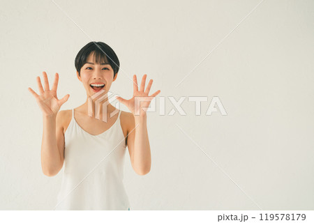 白い背景の前でキャミソール姿の若い女性が手のひらを見せるシーン 119578179