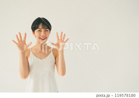白い背景の前でキャミソール姿の若い女性が手のひらを見せるシーン 119578180
