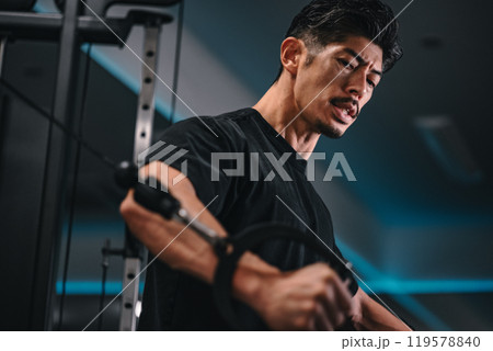 ジムでマシンを使ってトレーニングをする男性 119578840