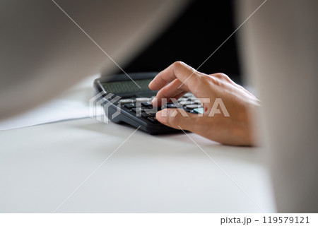 Focused Businesswoman Using Calculator for Financial Analysis in Modern Office Setting 119579121