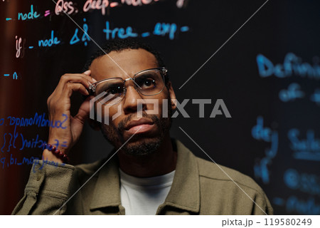 Thoughtful Man Analyzing Data on Transparent Board 119580249