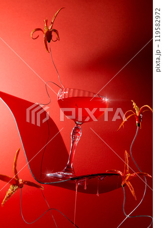 A fiery crimson cocktail tilted to the right on a curvaceous red platform, garnished with cut flowers from hot peppers against a seductive red background. Frontal image template for bar ads. A fiery crimson cocktail tilted to the right on a curvaceous red platform, garnished with cut flowers from hot peppers against a seductive red background. Frontal image template for bar ads. 119582972