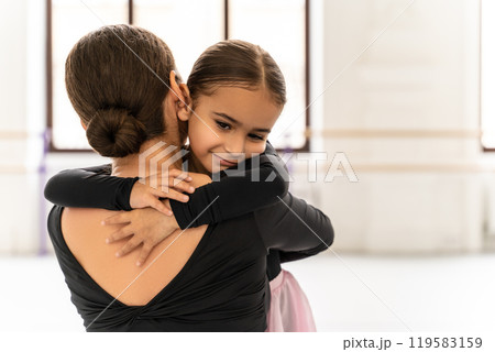 Teacher hugging her small student after ballet dance class in studio celebrating young dancer’s progress Teacher hugging her small student after ballet dance class in studio celebrating young dancer’s progress 119583159
