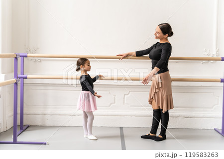 Ballet teacher training little girl at ballet barre in studio 119583263