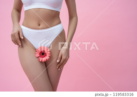 Woman wearing feminine lingerie holding gerbera flower symbolizing fertility and protection 119583316