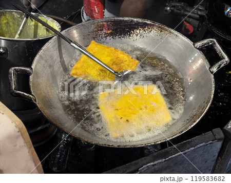 Fried omelet are fried in a steel skillet. 119583682