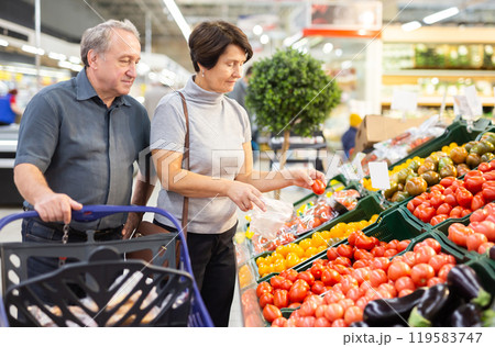 Mature woman and man selecting vegetables in greengrocer 119583747