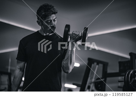 ジムでダンベルトレーニングする男性 119585127