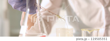 Laboratory worker pours urine into test tube using pipette 119585351
