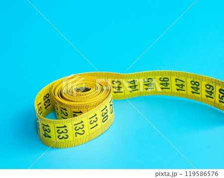 Yellow centimeter tape measure on blue background 119586576