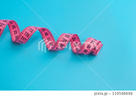 Pink centimeter tape measure on blue background Pink centimeter tape measure on blue background 119586698