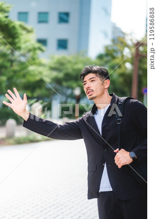 ビジネス街でタクシーを止める男性 119586888