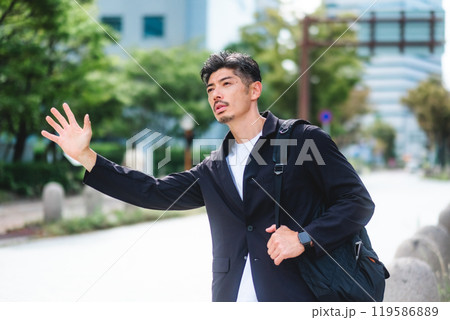 ビジネス街でタクシーを止める男性 ビジネス街でタクシーを止める男性 119586889