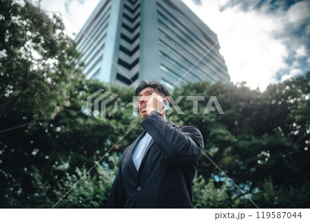 ビル群でスマホを持つ男性 119587044