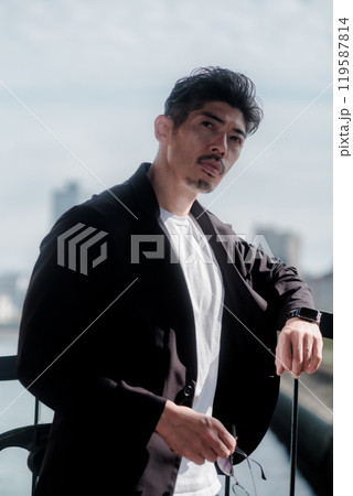 海辺に佇むセットアップを着た男性 119587814