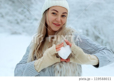 I like winter. Portrait of a happy young girl holding a snowy heart in her hand during winter time. Valentine's Day. I like winter. Portrait of a happy young girl holding a snowy heart in her hand during winter time. Valentine's Day. 119588011